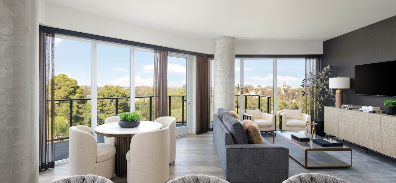 Living Room Spacious and well lit living room with wood floors and large floor to ceiling windows with a city view.